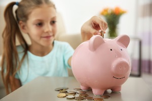 Girl adding coins to piggy bank
