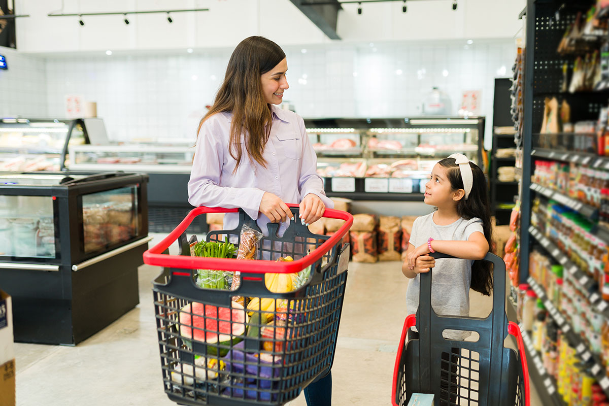 Woman and girl pushing shopping carts at grocery store
