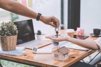 arm handing another arm keys over a model home
