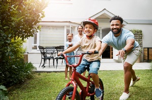 Man pushing boy on bike with woman and girl in background