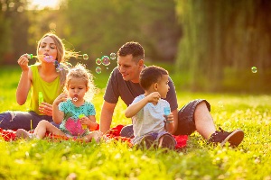 Happy family in the park- family with children blow soap bubbles outdoor.