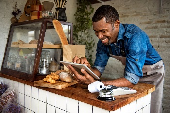 Man standing at bakery counter looking at ipad