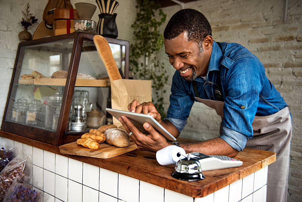 Man standing at bakery counter looking at ipad