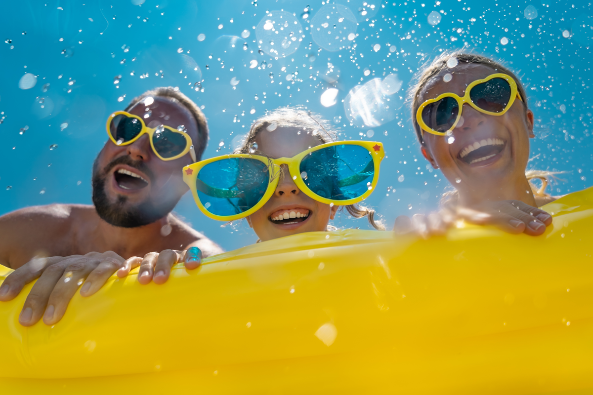 Two adults and a child wearing sunglasses on an intertube in water