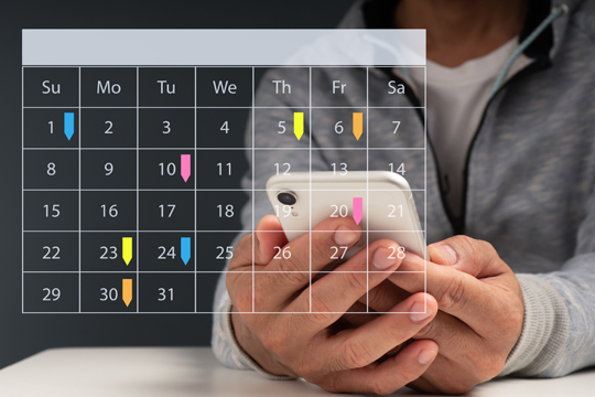 person holding smart phone with an overlay of a calendar