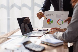 Two people colaborating with a laptop and charts