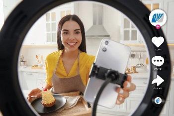 Women in yellow shirt putting her phone on a stand to film a cooking tiktok