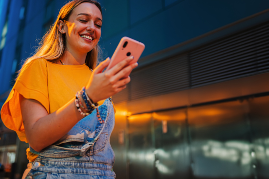 girl in bright colors happy and looking at her phone
