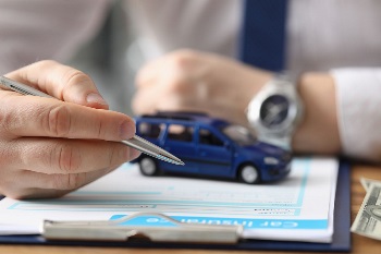 Male hand hold pen on clip board with toy car