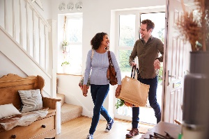 Couple walking into home with groceries