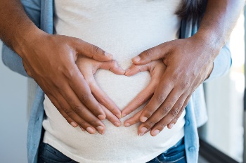 Couple making heart on pregnant belly