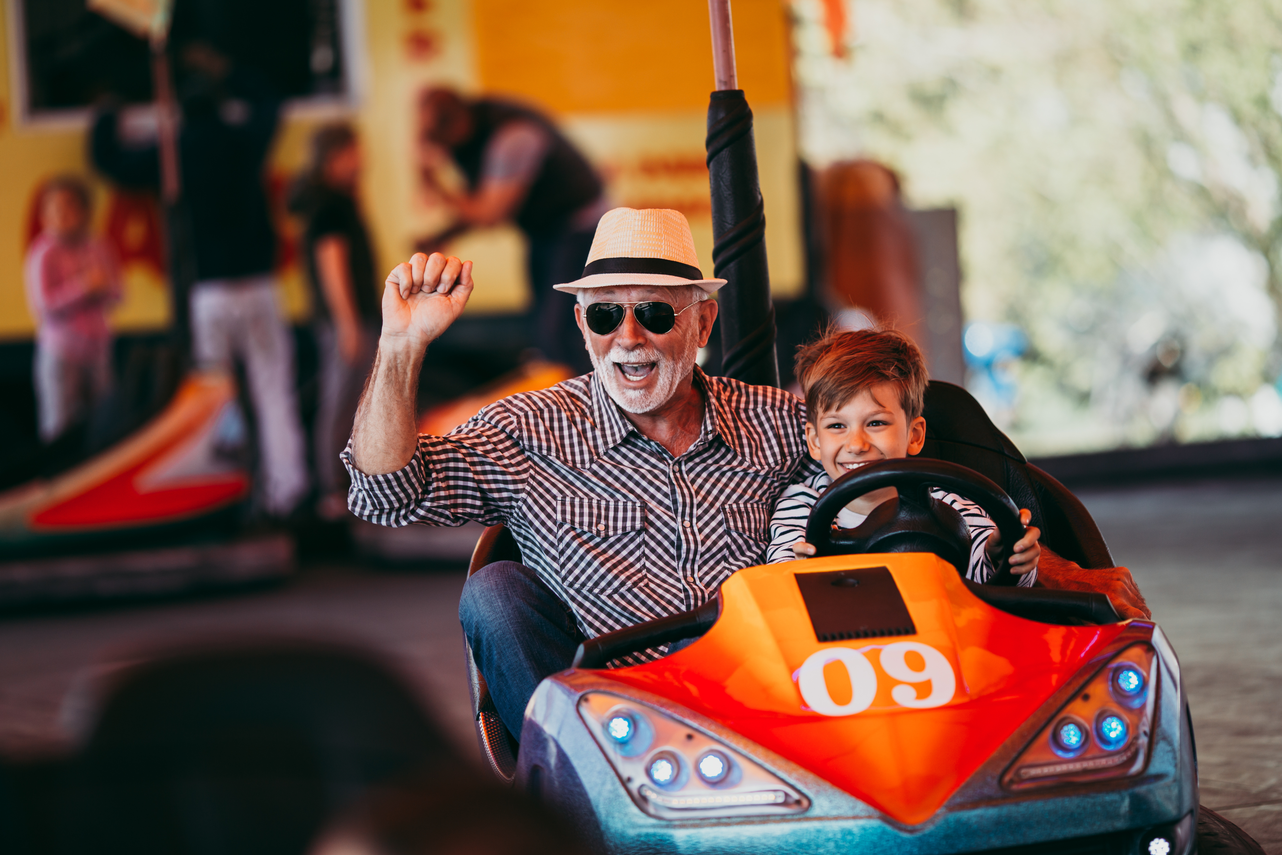 Little boy and older man riding in bumper car together