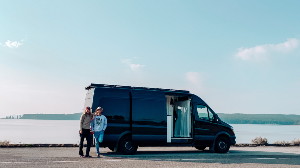 Couple standing in front of a van by a lake