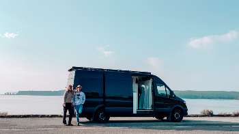 Couple standing in front of a van by a lake
