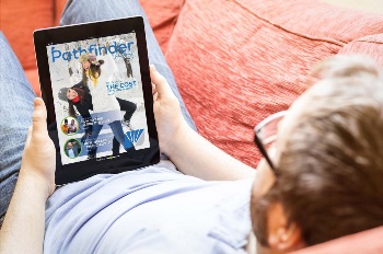 Guy laying on couch reading magazine on tablet