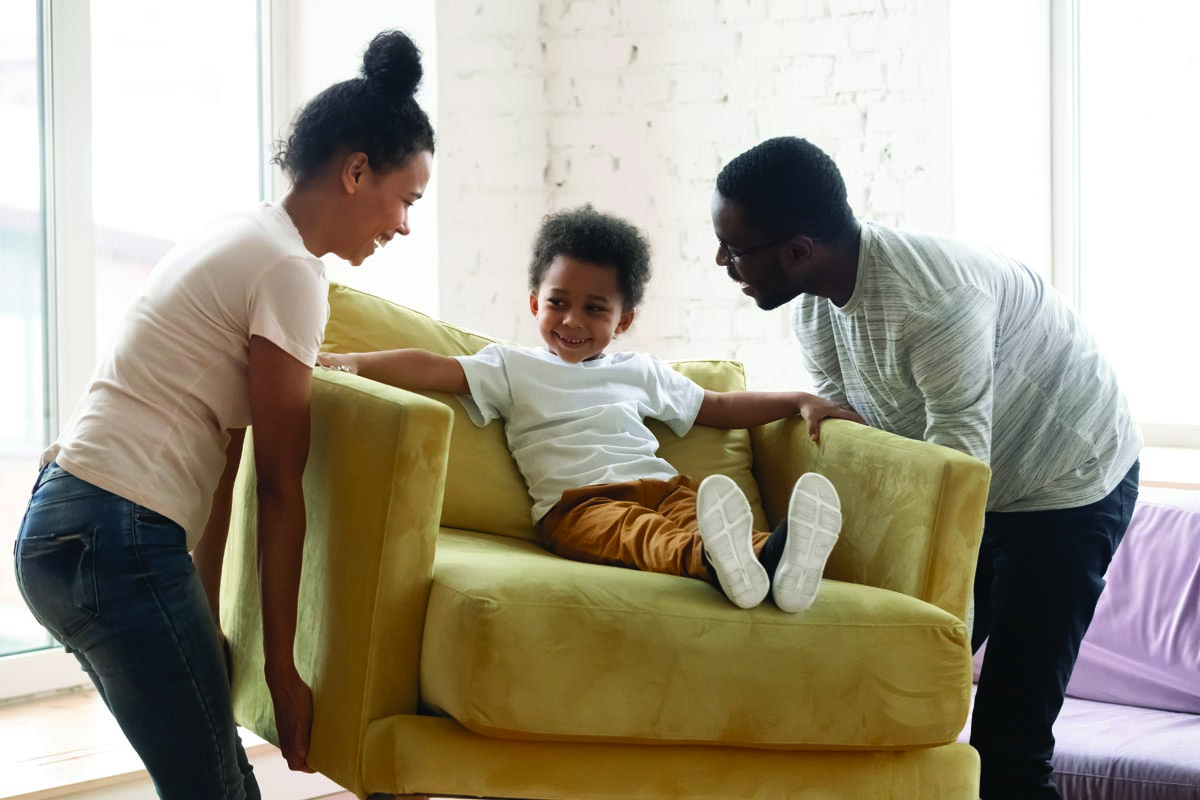 Mom and dad picking up a chair with their toddler sitting on it