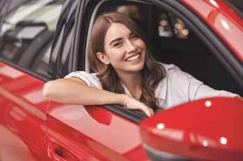 Woman looking happy sitting in a red car