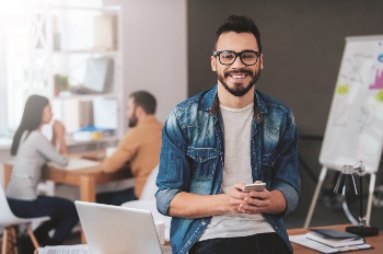 Young man sitting in workspace on cellphone