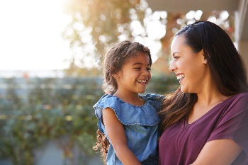 Hispanic mom and young daughter laughing