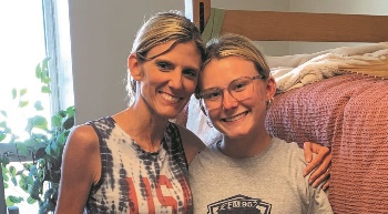 Mom and daughter in daughter's college dorm room posing for a picture