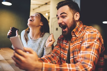 Excited man and woman holding phone