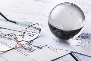 Crystal ball on top of economic forecast papers