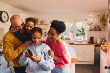 Family of four looking at their oldest girls' phone and smiling