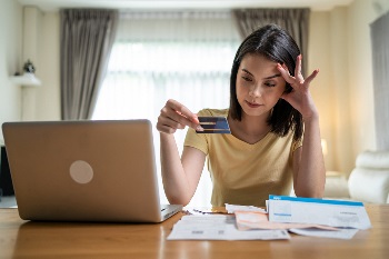 Woman holding credit card looking stressed
