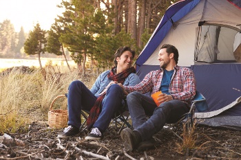 Couple sitting outside a tent in the wilderness looking lovingly at each other
