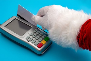 Santa's hand swiping a credit card in a machine
