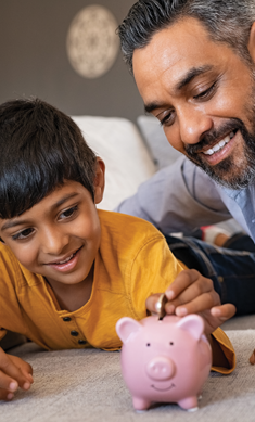 Man and boy putting money in piggy bank