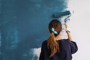 young woman painting wall blue